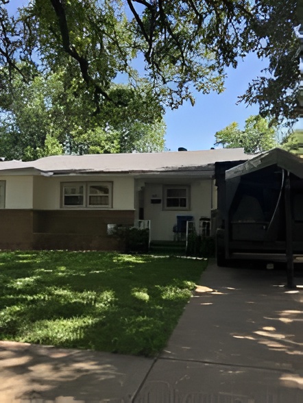 Completed low-slope roof replacement on a tan brick ranch home in Fort Worth