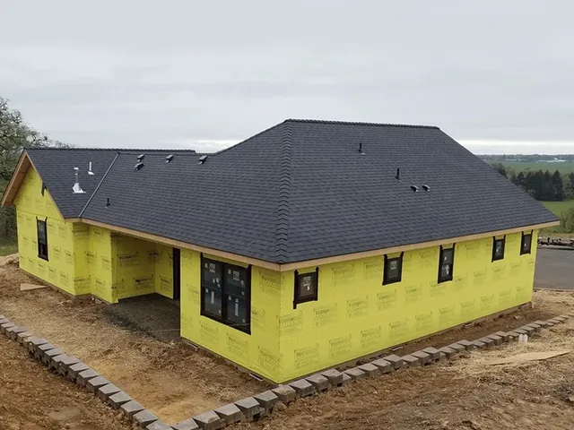 Newly installed charcoal shingle hip roof on a home under construction