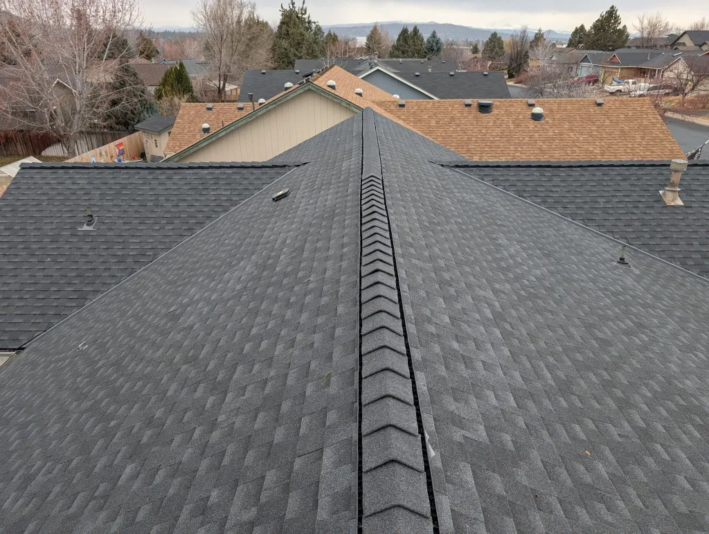 Close view along a roof ridge with new ridge vent and charcoal architectural shingles